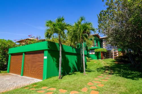 um edifício verde e laranja com palmeiras em frente a uma casa em Quintas de Sauípe - Casa K06 na Costa do Sauípe