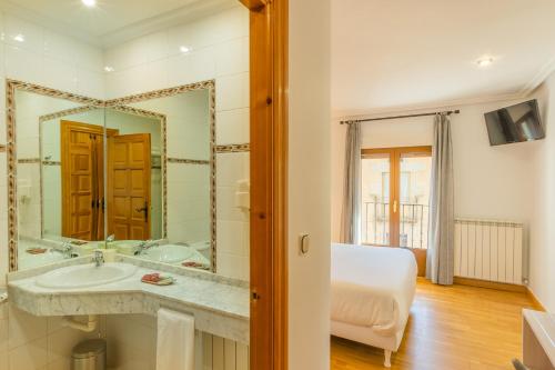 a bathroom with a sink and a large mirror at Hostal Gran Duque in Piedrahita