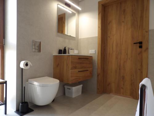 a bathroom with a toilet and a wooden door at Apartamenty TAFLA nad Jeziorem Czorsztyńskim in Kluszkowce