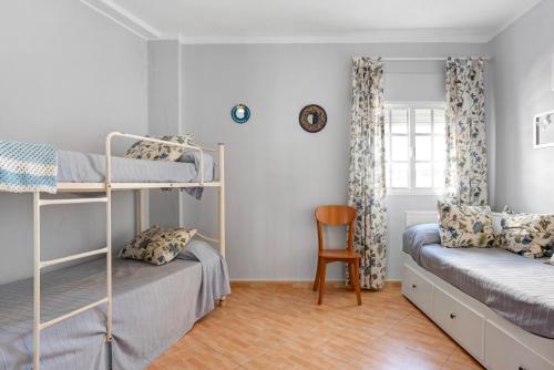 a bedroom with two bunk beds and a chair at Apartamento Goya in Conil de la Frontera
