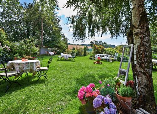 a garden with a table and chairs and flowers at Romantik Hotel Zum Rosenhof in Hesserode