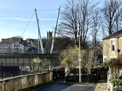 a suspension bridge over a road with a castle in the background at River Terrace in Lancaster