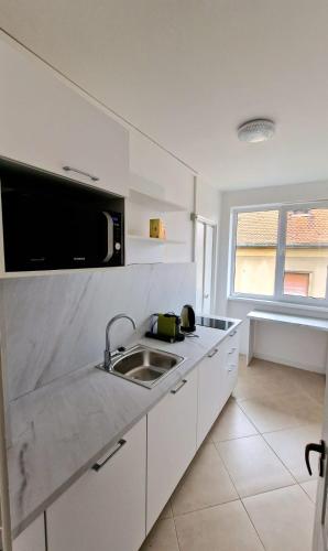 cocina blanca con fregadero y microondas en PREFECTURE APARTMENTS, en Timisoara