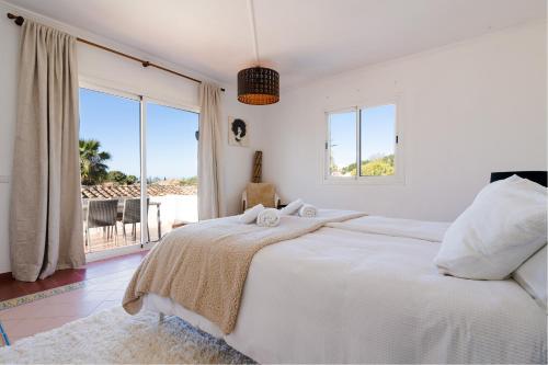 マルベーリャにあるCasa Alejandroの白いベッドルーム(ベッド1台、大きな窓付)