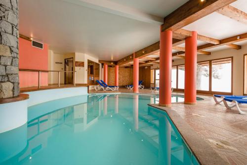 a swimming pool in a hotel with chairs and tables at Lagrange Vacances L'Arollaie in Peisey-Nancroix