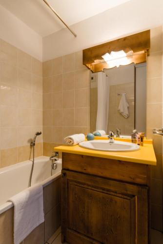 a bathroom with a sink and a tub and a mirror at Lagrange Vacances L'Arollaie in Peisey-Nancroix