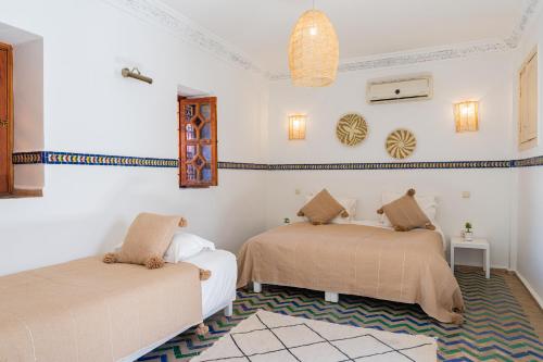 2 Betten in einem Zimmer mit weißen Wänden in der Unterkunft Riad Le Marocain in Marrakesch