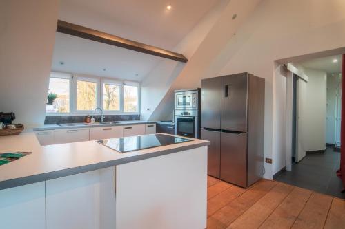eine Küche mit weißen Schränken und einem Kühlschrank aus Edelstahl in der Unterkunft Villa avec vue panoramique in Charleville-Mézières