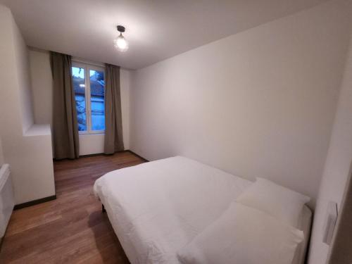 1 dormitorio con cama blanca y ventana en Agréable appartement, lumineux, en Bar-le-Duc