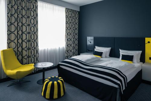 a bedroom with a large bed and a yellow chair at Vienna House by Wyndham Andel's Berlin in Berlin