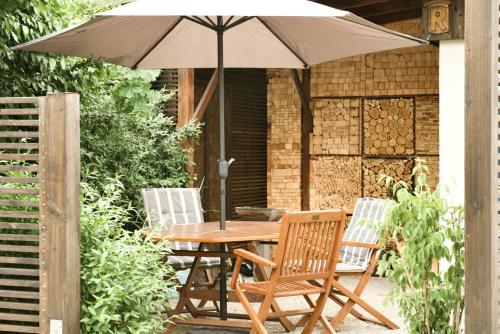 a wooden table with two chairs and an umbrella at Villa B - Neuer Geist in alten Mauern: luxuriös Wohnen in der Residenzstadt Gotha in Gotha