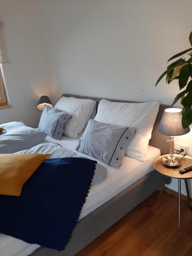Una cama con almohadas blancas y una mesa con una planta. en Studio mit großer Loggia, en Saalfelden am Steinernen Meer