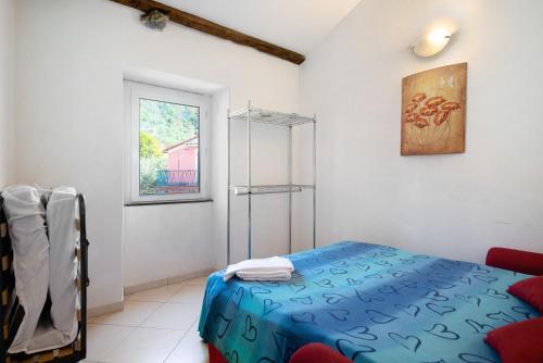 a bedroom with a blue bed and a window at Bilocale Serra in Bonassola