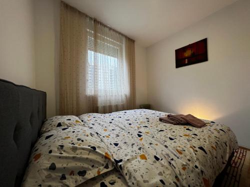 - une chambre avec un lit doté d'une couette et d'une fenêtre dans l'établissement Sunrise Apartment in Prishtina, Kosovo, à Pristina