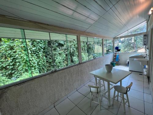 a room with a table and chairs and windows at Aconchego em Teresópolis com piscina privativa próximo a feirinha in Teresópolis