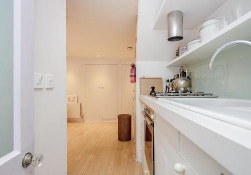 uma cozinha com um balcão branco e um lavatório em Notting Hill London - Chic Bright Apartment W11 em Londres