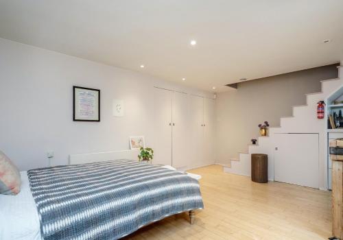 1 dormitorio con 1 cama y escalera en Notting Hill London - Chic Bright Apartment W11, en Londres