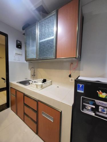 a kitchen with wooden cabinets and a black refrigerator at Apartemen springwood in Pakulonan Dua