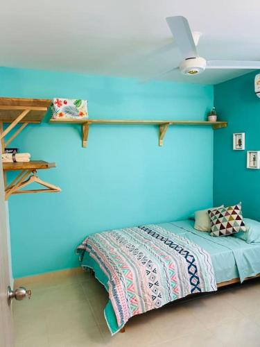 Un dormitorio con una pared azul con una cama y estanterías en Casa ideal vacaciones o trabajo, en Santa Marta