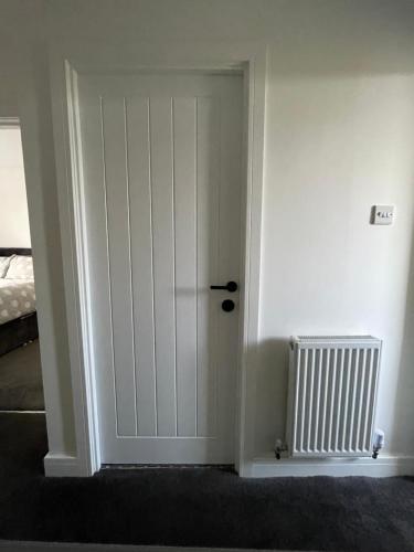 a white door in a room with a bed at VA Home Stay - Close to Luton Airport, M1 & A505 in Luton