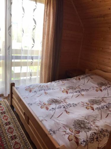 1 dormitorio con 1 cama con colcha de flores en Модрина, en Vorokhta