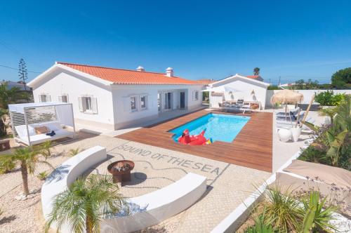 a villa with a swimming pool in front of a house at Villa Sound of the Sea by Portugal Collection in Aljezur