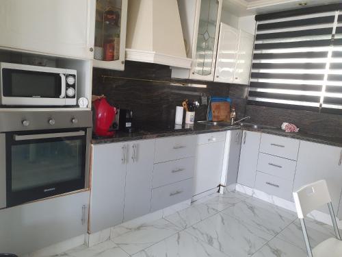eine Küche mit weißen Schränken und einer Mikrowelle in der Unterkunft BELLE CHAMBRE CONFORTABLE in Netanya