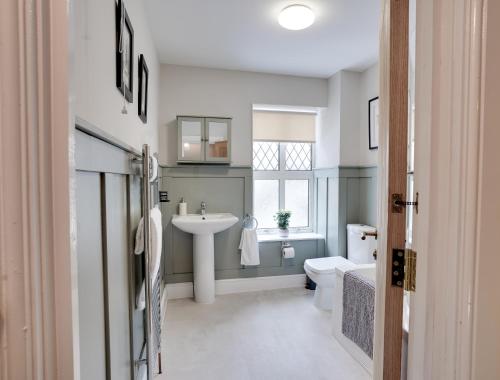 ein Badezimmer mit Waschbecken und Toilette und einem Fenster in der Unterkunft Sage Cottage Buxton Family Getaway with Log Fire in Buxton