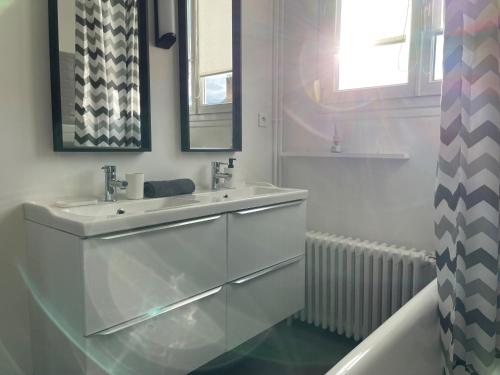 La salle de bains blanche est pourvue d'un lavabo et d'un miroir. dans l'établissement Le cinquante-deux appartement de Charme, à Reims