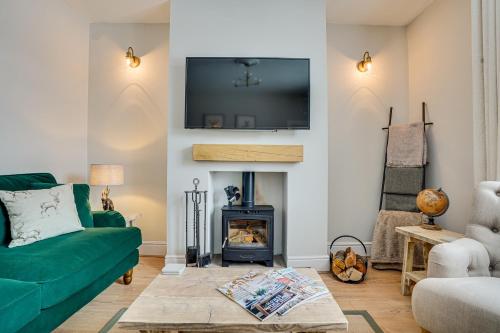 uma sala de estar com um sofá verde e uma lareira em Sage Cottage: Homely, Cosy Cottage with Log Burner em Buxton