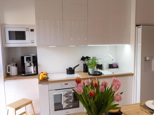 a kitchen with white cabinets and a vase of flowers at Apartamenty TAFLA nad Jeziorem Czorsztyńskim in Kluszkowce
