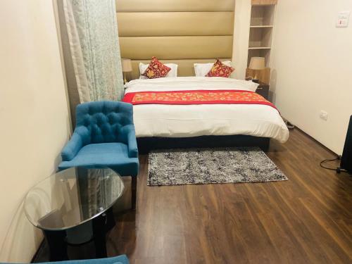 ein Schlafzimmer mit einem Bett und einem blauen Stuhl in der Unterkunft Himalayan Sun Cottage in Srinagar