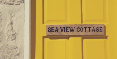 een gele deur met een bord met uitzicht op zee bij Sea View Cottage in Portland