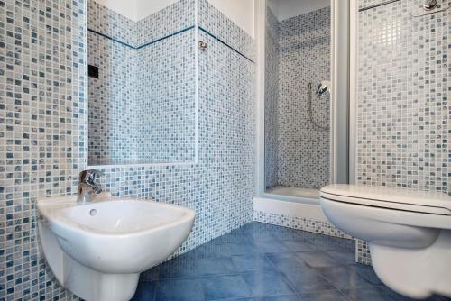 a blue tiled bathroom with a toilet and a sink at Serra Monolocale in Bonassola