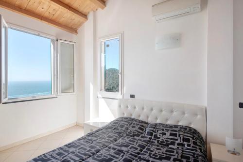 a white bedroom with a bed and two windows at Serra Monolocale in Bonassola