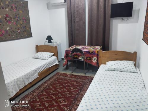 a room with two beds and a table and a rug at Hotel Mosque Baland in Bukhara