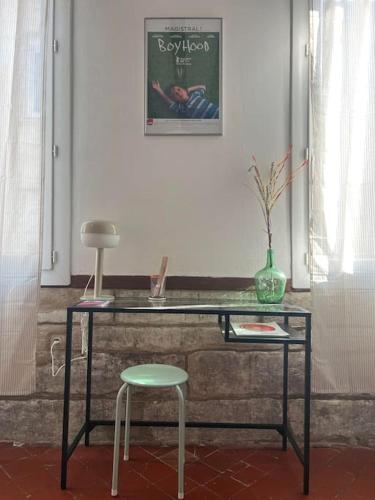 mesa de cristal con taburete y silla en una habitación en Studio au cœur du centre ville d’Avignon, en Aviñón