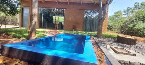 a blue swimming pool in front of a house at Hartbees Eco Bush Lodge 1 in Hartbeespoort