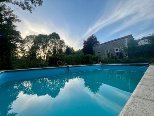 una piscina de agua azul frente a una casa en Domaine du Banaret - authentic stone house at the heart of Périgord Vert, en Bussière-Badil