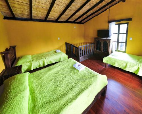 two beds in a room with green sheets at La Posada Campestre Cabañas in El Cocuy