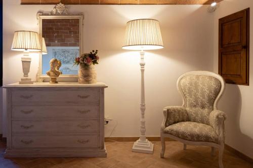 a bedroom with a dresser and a lamp and a chair at Lajatico Rentals - Terrazza sul Tramonto del Silenzio in Laiatico