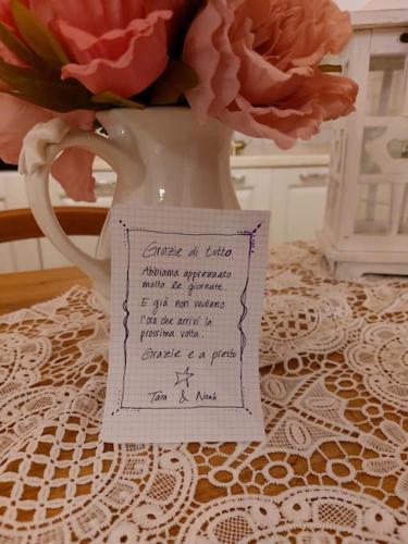 a vase filled with flowers on a table with a note at Lajatico Rentals - Terrazza sul Tramonto del Silenzio in Laiatico