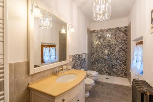 baño con lavabo, aseo y lámparas de araña en Terrazza sul Tramonto del Silenzio, en Lajatico