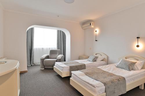 a hotel room with two beds and a chair at Makis Hotel SPA in Lutsk