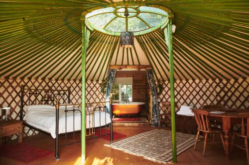a bedroom in a yurt with a bed and a table at Nature's Spectacular in Chew Stoke