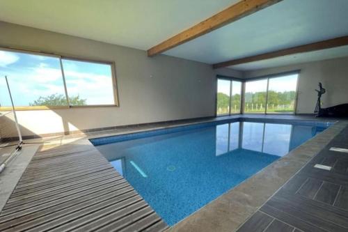 ein Pool mit blauem Wasser in einem Haus in der Unterkunft Magnifique villa avec piscine intérieure in Saint-Pois