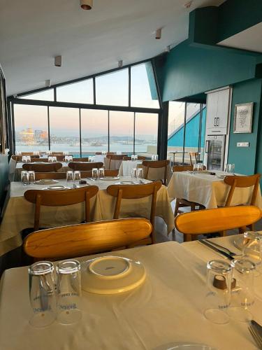a restaurant with white tables and chairs and windows at Riva's Moda in Istanbul