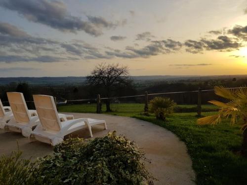 a group of white chairs sitting on a path at Magnifique villa avec piscine intérieure in Saint-Pois