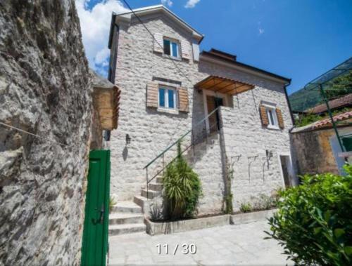 a stone house with a green door and stairs at Holiday Home Bogumila in Risan