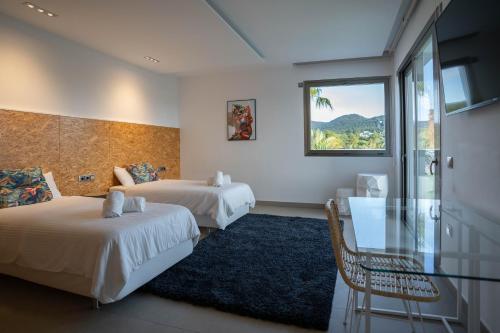 a hotel room with two beds and a glass table at Es Maiols Casa B in Can Furnet